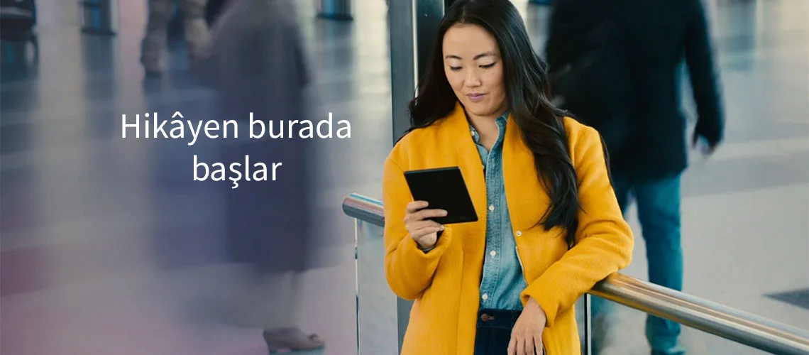 Amazon Kindle 10. Nesil e-kitap okuyucu kullanan bir kadın okuma yapıyor, görselde “Hikâyen burada başlar” sloganı yer alıyor